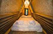Vista interna di una tenda safari di lusso al Trasimeno Glamping Resort in Italia, con letto grande e legno.