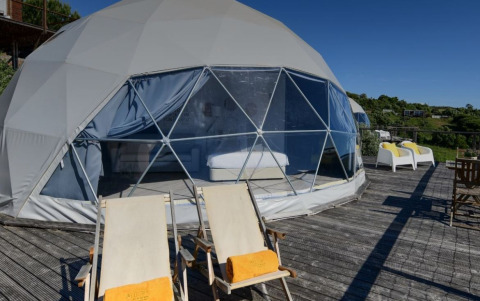 ‘Family Domes’ koepel op Wecamp Reserva Alecrim in Portugal, met ligstoelen en uitzicht op de natuur.