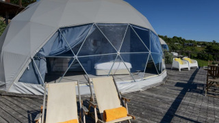‘Family Domes’ koepel bij Wecamp Reserva Alecrim, Portugal, met ligstoelen op een houten terras.