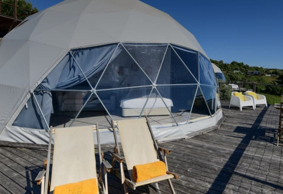 ‘Family Domes’ koepel op Wecamp Reserva Alecrim in Portugal, met ligstoelen en uitzicht op de natuur.