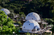 Family Domes in Wecamp Reserva Alecrim, Portugal, omringd door bomen en verhoogde houten wandelpaden.
