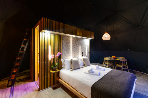 Moderne slaapkamer in Family Domes van Wecamp Reserva Alecrim Portugal, met houten details en sfeerverlichting.