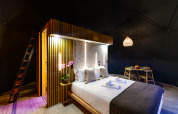 Moderne slaapkamer in Family Domes van Wecamp Reserva Alecrim Portugal, met houten details en sfeerverlichting.