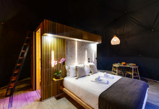Moderne slaapkamer in Family Domes van Wecamp Reserva Alecrim Portugal, met houten details en sfeerverlichting.