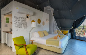 Binnenzicht van Couple Domes bij Wecamp Reserva Alecrim in Portugal met bed, zetel en muskietennet.