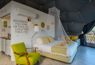 Binnenzicht van Couple Domes bij Wecamp Reserva Alecrim in Portugal met bed, zetel en muskietennet.