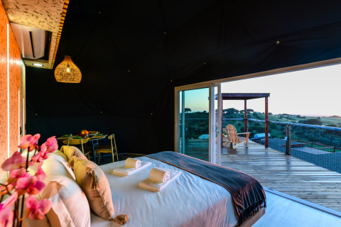 Binnenzicht van een koepel in Family Domes, Wecamp Reserva Alecrim, Portugal, met bed en terras met uitzicht.