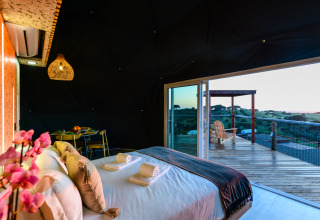Binnenzicht van een koepel in Family Domes, Wecamp Reserva Alecrim, Portugal, met bed en terras met uitzicht.