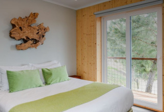 Slaapkamer in Dome House Duplex bij Wecamp Reserva Alecrim, Portugal, met houten inrichting en groene kussens.