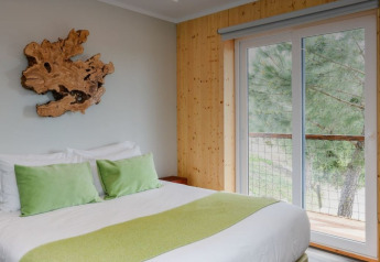 Dormitorio en Dome House Duplex en Wecamp Reserva Alecrim, Portugal, con decoración en madera y cojines verdes.