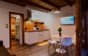 Vista interior del Bungalow «Family Wood» con cocina, mesa de comedor y TV en Wecamp Reserva Alecrim.