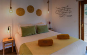 Dormitorio acogedor con almohadas verdes y toallas amarillas en Bungalow Family Wood, Wecamp Reserva Alecrim, Portugal.