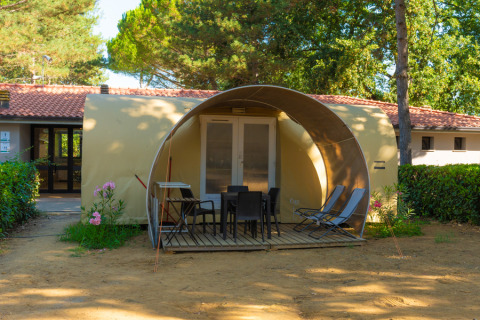 Safari-tent Coco Suite met terras, tuinstoelen en ligzetels, omgeven door bomen en bloemen.