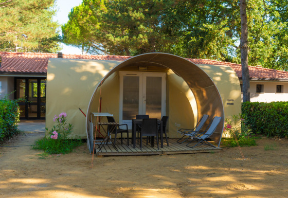Safari-tent Coco Suite met terras, tuinstoelen en ligzetels, omgeven door bomen en bloemen.