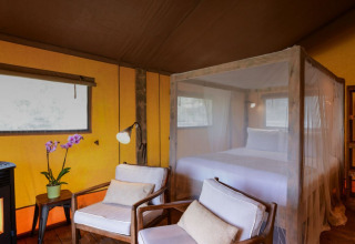 Interieur van een safaritent Lodge Family bij Wecamp Reserva Alecrim in Portugal met bed en zetels.