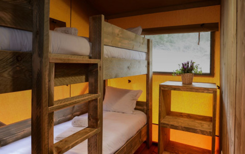 Binnenzicht van een Lodge Family safaritent met stapelbedden en houten meubels bij Wecamp Reserva Alecrim.