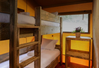 Interieur van een Lodge Family safaritent met stapelbedden en houten meubels bij Wecamp Reserva Alecrim, Portugal.
