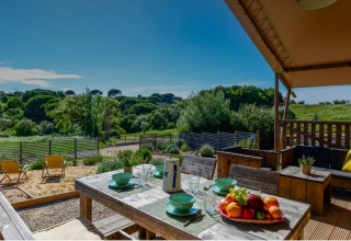 Buitenterras met tafel en zicht op natuur bij Lodge Family safaritent, Wecamp Reserva Alecrim, Portugal.