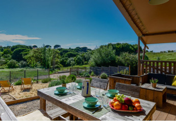 Terrasse mit Esstisch, Obstschale und Blick auf die Natur im Lodge Family Safarizelt, Portugal.
