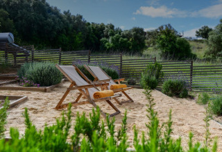 Ontspanningshoek met strandstoelen en handdoeken in het zand bij Lodge Family, Wecamp Reserva Alecrim, Portugal.