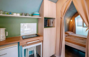 Interno della tenda safari «Coco Suite» con cucina e camera da letto al Trasimeno Glamping Resort in Italia.