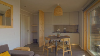 Acogedora sala y cocina en Bungalow Comfort Family en Wecamp Reserva Alecrim, Portugal, con mesa y sillas de madera.