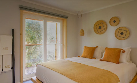 Lichtrijke slaapkamer met gele kussens in Bungalow Comfort Family, Wecamp Reserva Alecrim, Portugal.