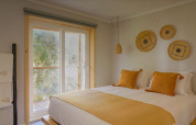 Lichtrijke slaapkamer met gele kussens in Bungalow Comfort Family, Wecamp Reserva Alecrim, Portugal.