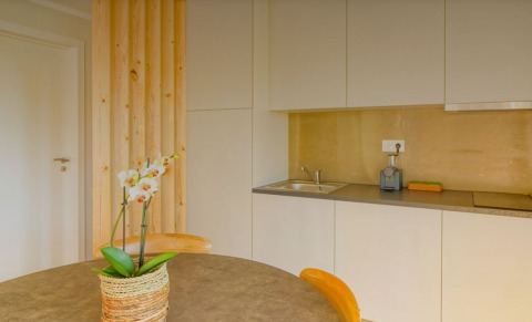 Moderne kitchenette in Bungalow Comfort Family bij Wecamp Reserva Alecrim, Portugal, met tafel en orchidee.