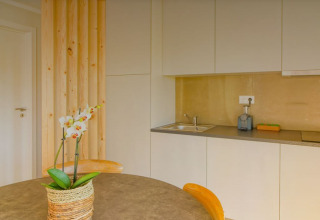 Moderne kitchenette in Bungalow Comfort Family bij Wecamp Reserva Alecrim, Portugal, met tafel en orchidee.