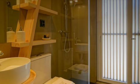Moderne badkamer met houten rekken en regendouche in Bungalow Comfort Family, Wecamp Reserva Alecrim, Portugal.