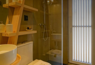 Moderne badkamer met houten rekken en regendouche in Bungalow Comfort Family, Wecamp Reserva Alecrim, Portugal.