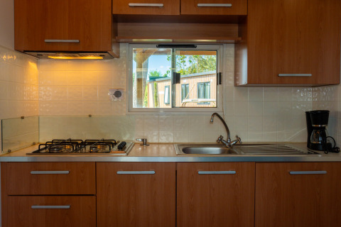 Cocina moderna en Cottage Classic, Trasimeno Glamping Resort, Italia. Armarios de madera, estufa, cafetera.