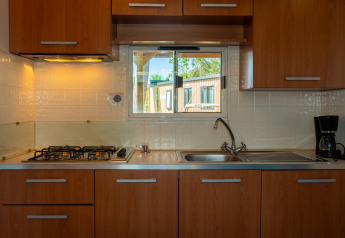 Cocina moderna en Cottage Classic, Trasimeno Glamping Resort, Italia. Armarios de madera, estufa, cafetera.