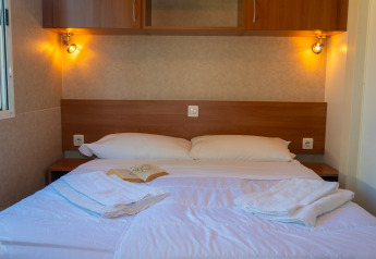 Chambre de lodge confortable avec lit double, oreillers blancs, serviettes et éclairage tamisé.