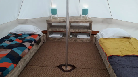 Interno di una tenda Bell Tent a Wecamp Sao Miguel, Portogallo, con due letti e arredo in legno.