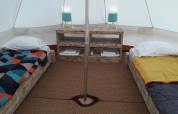 Interior de una tienda tipi Bell Tent en Wecamp Sao Miguel, Portugal, con dos camas y muebles rústicos.
