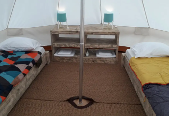 Intérieur d'une tente tipi Bell Tent à Wecamp Sao Miguel, Portugal, avec deux lits et mobilier en bois.