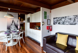 Modern gezinsbungalow interieur bij Wecamp Reserva Alecrim, Portugal met eettafel, keuken en zetel.