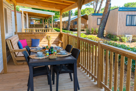Terraza de madera en la Cottage Classic en Trasimeno Glamping Resort, Italia, con mesa y banco.
