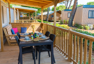 Terraza de madera en la Cottage Classic en Trasimeno Glamping Resort, Italia, con mesa y banco.
