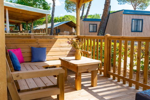 Terraza de madera con asientos y cojines de colores en Cottage Classic, Trasimeno Glamping Resort, Italia.