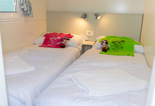 Dos camas individuales con camisetas coloridas y peluches en una habitación Cottage Classic en Trasimeno Glamping Resort.