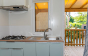 Cucina del Cottage Classic al Trasimeno Glamping Resort, con fornelli a gas, lavello e vista sulla veranda.