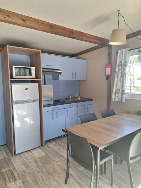 Keukenzone in Bungalow Family Premium bij Wecamp Sao Miguel, Portugal, met eettafel en koelkast.