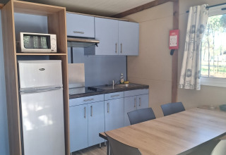 Keukenzone in Bungalow Family Premium bij Wecamp Sao Miguel, Portugal, met eettafel en koelkast.