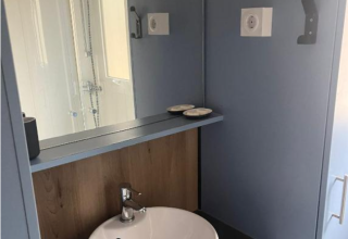 Moderne badkamer met ronde wastafel, spiegel en douche in Bungalow Family Premium, Wecamp Sao Miguel, Portugal.
