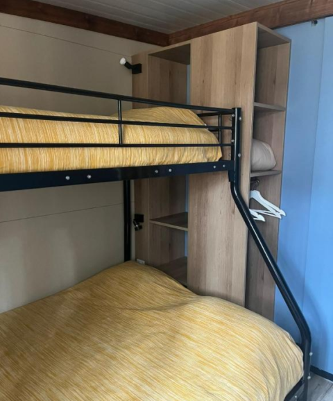Stapelbed met gele dekens en open kast in Bungalow Family Premium op Wecamp Sao Miguel, Portugal.