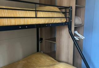 Stapelbed met gele dekens en open kast in Bungalow Family Premium op Wecamp Sao Miguel, Portugal.