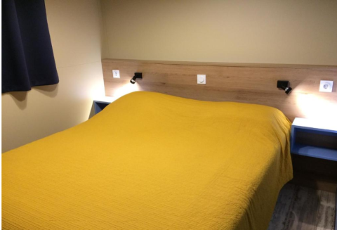 Kamer van Bungalow Family Premium, Wecamp Sao Miguel, Portugal, met dubbel bed en gele sprei.